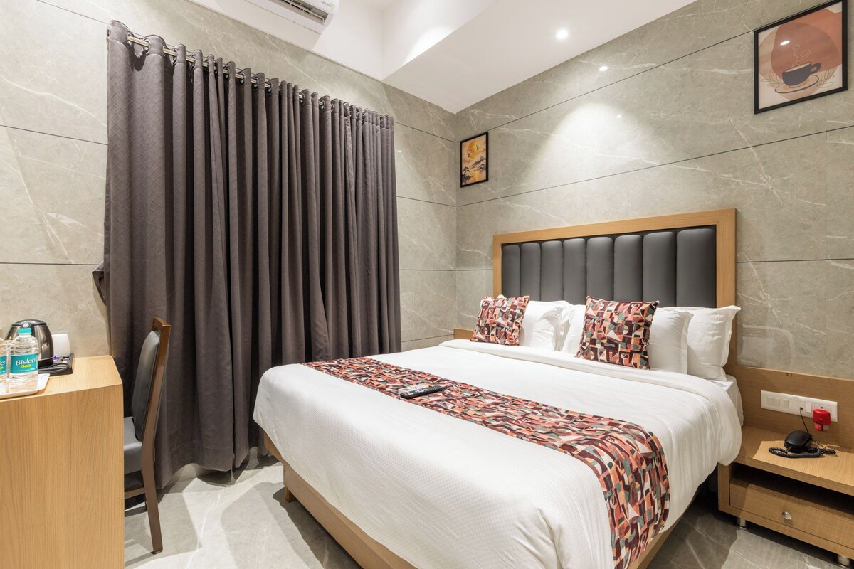 Una habitación de hotel con una cama, un escritorio, una silla y una mesita de noche.
