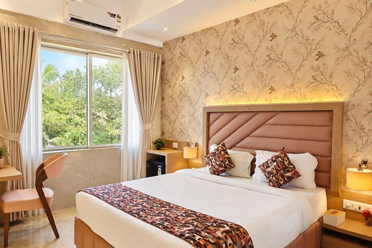 Een hotelkamer met een groot bed, een bureau, een stoel en een raam met gordijnen.