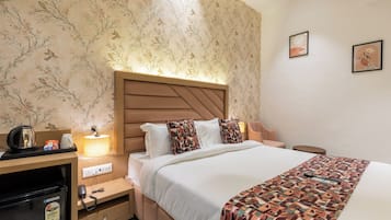 A hotel room with a bed, bedside table, lamp, and a wall with floral wallpaper.