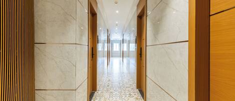 A corridor with marble walls and a patterned floor, leading to a bright interior space.