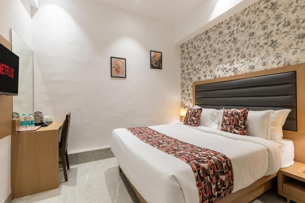 Une chambre d’hôtel équipée d’un lit, d’un bureau avec un ordinateur, d’une chaise et d’un écran de télévision affichant « NETFLIX ».