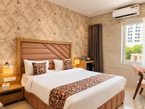 Habitación de hotel con una cama grande, una mesita de noche, aire acondicionado, una ventana con cortinas y vistas a un edificio.