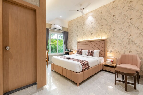 A bedroom with a bed, bedside table, chair, and an air conditioning unit. - Stellos Hotel Mumbai (Mumbai)