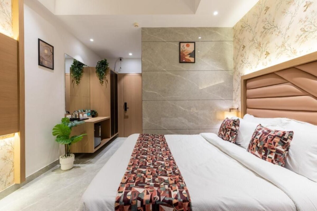 Un dormitorio moderno con una cama grande, cabecera, mesita de noche, espejo y una planta en maceta.