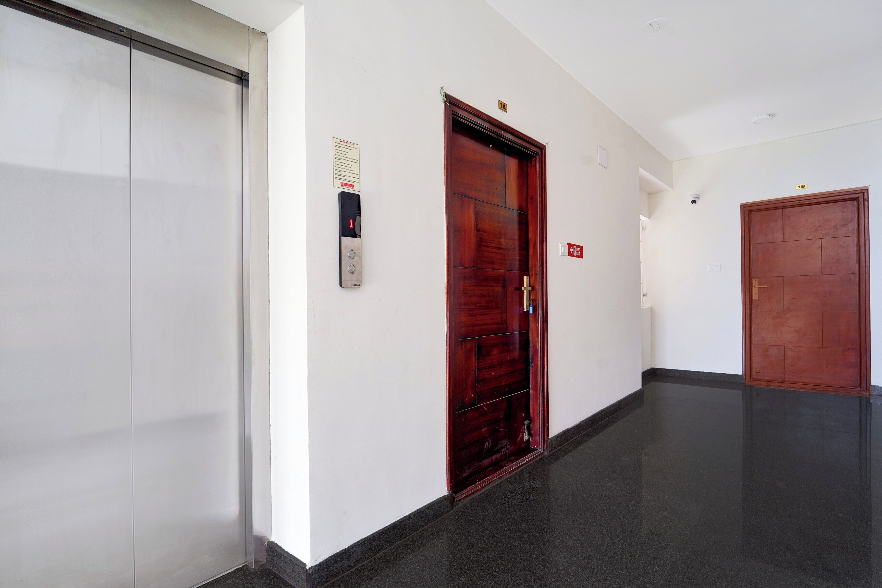 Un pasillo con un ascensor blanco, una puerta de madera y un cartel de seguridad contra incendios.