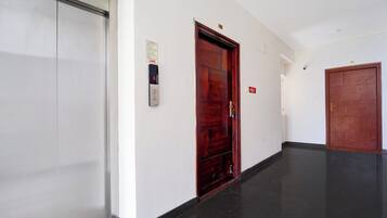 Un pasillo con un ascensor blanco, una puerta de madera y un cartel de seguridad contra incendios.