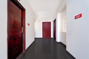 A corridor with wooden doors and a red exit sign. - Townhouse Svb Tech Park Kalapatti (Coimbatore)