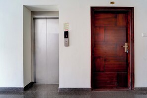 Un ascensor con pantalla digital y puerta de madera con tirador de latón.