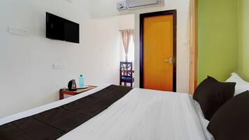 Habitación de hotel con cama, televisión, aire acondicionado, ventana con cortinas y puerta.
