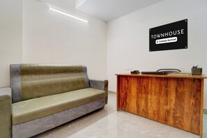 A reception area with a sofa and a wooden desk. - Townhouse Svb Tech Park Kalapatti (Coimbatore)