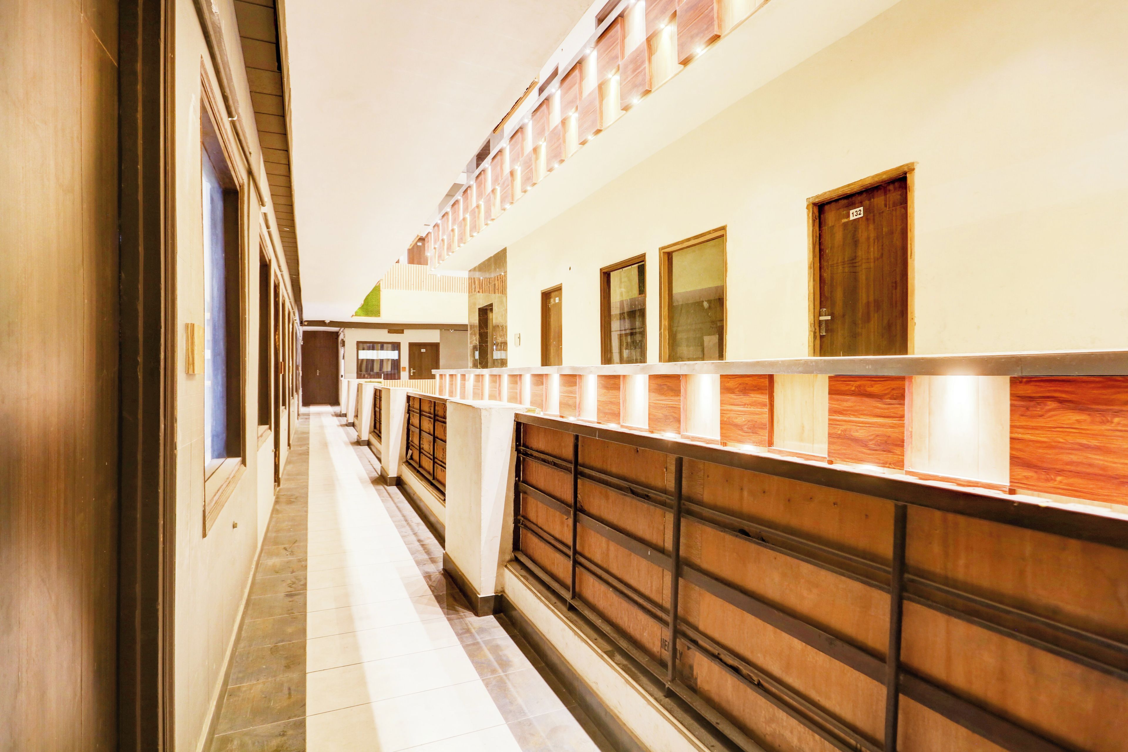 A corridor with a wooden railing, doors, and a tiled floor.