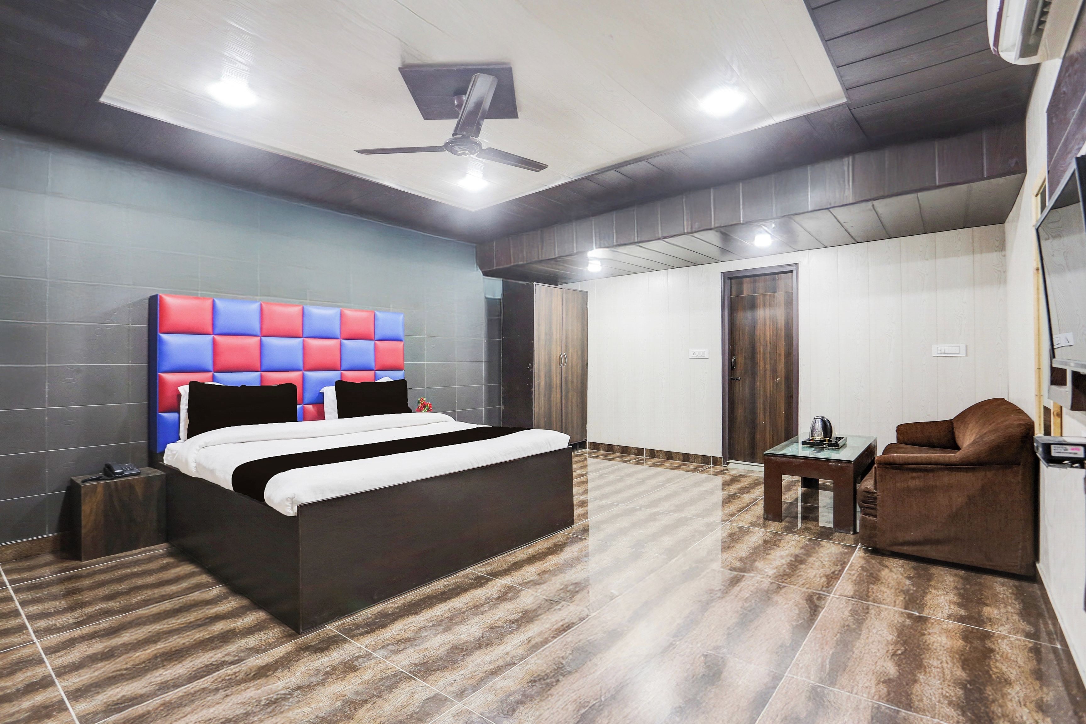 Ein modernes Hotelzimmer mit einem großen Bett, einem kleinen Tisch, einem Stuhl und einem Deckenventilator.