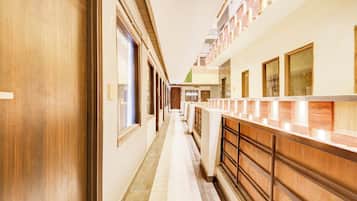 A hotel corridor with wooden doors, a reception desk, and a tiled floor.