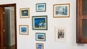 Paret amb diverses obres d'art emmarcades que representen paisatges costers i arquitectura.
