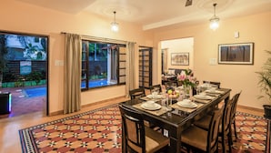 Un comedor con una mesa dispuesta para cuatro personas, un ventilador de techo y vista a una piscina exterior.
