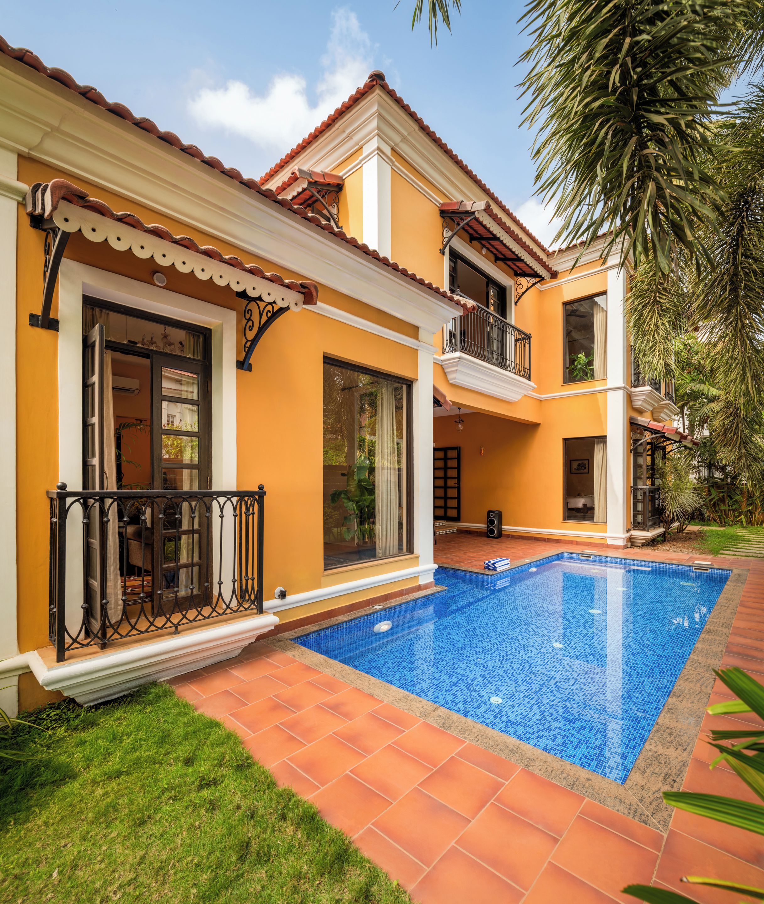 Una casa de dos pisos con piscina, balcón y jardín.