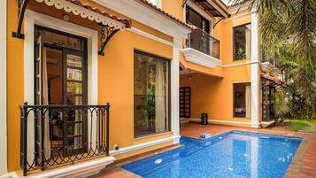 Una casa de dos pisos con piscina, balcón y jardín.