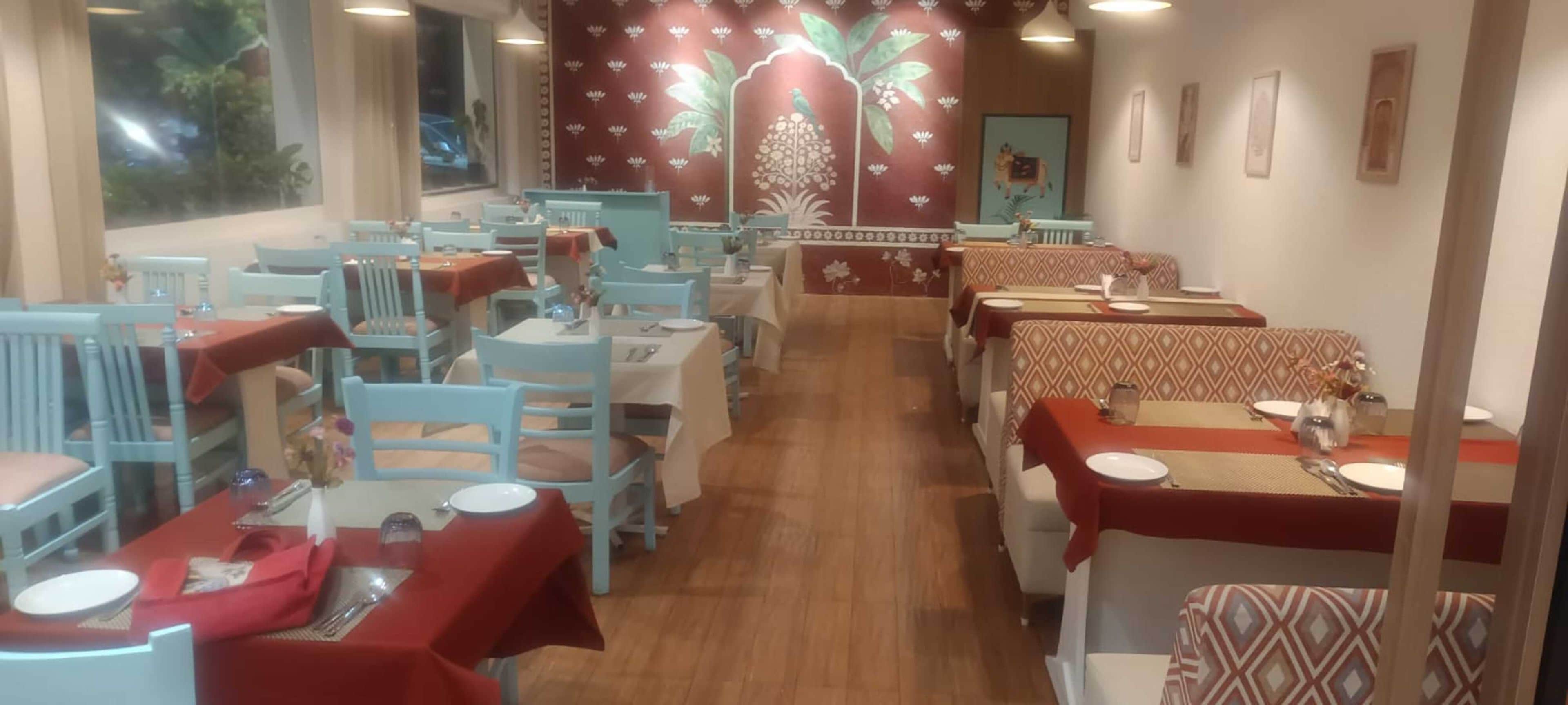 Un restaurante con varias mesas y sillas, algunas cubiertas con manteles rojos.