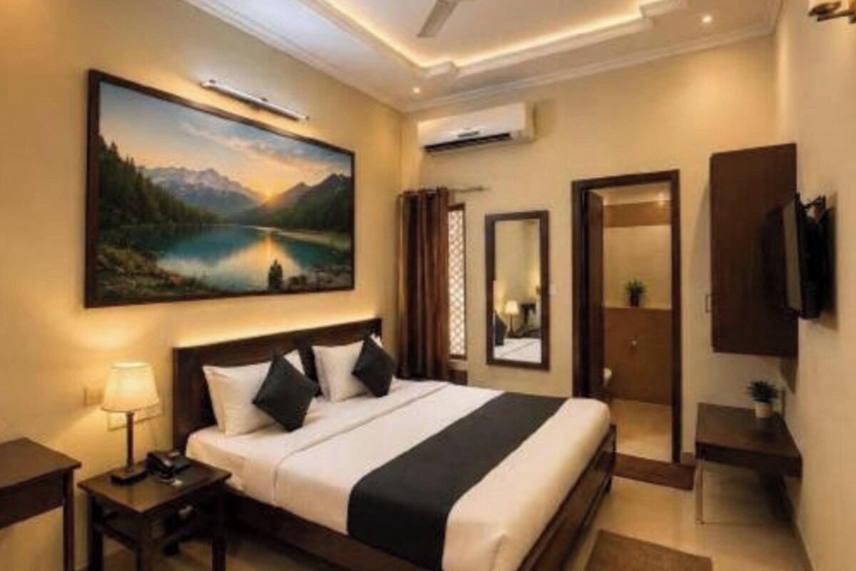 Une chambre d’hôtel avec un lit, un tableau, un ventilateur de plafond et un téléviseur.