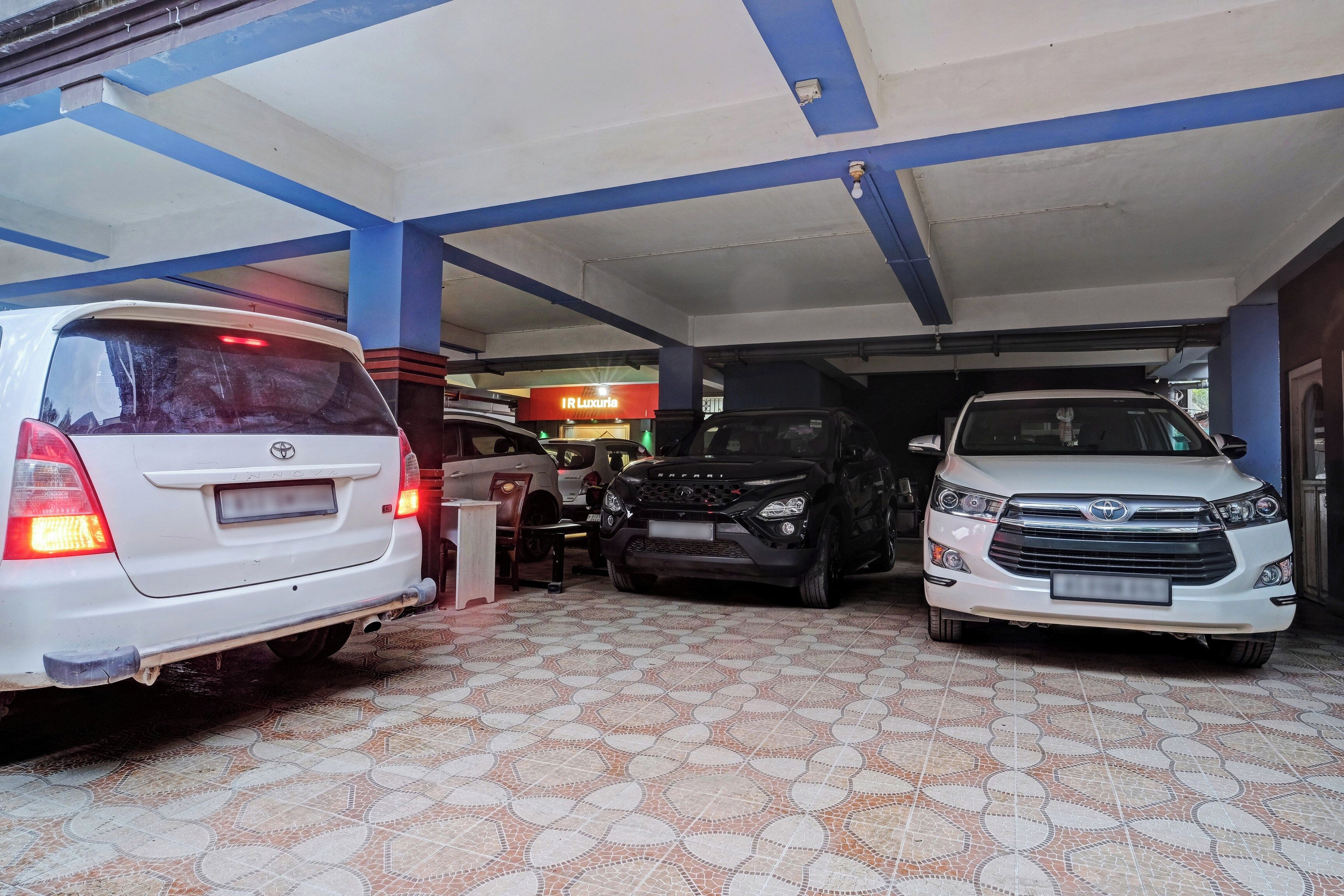 Un estacionamiento techado con tres coches aparcados.