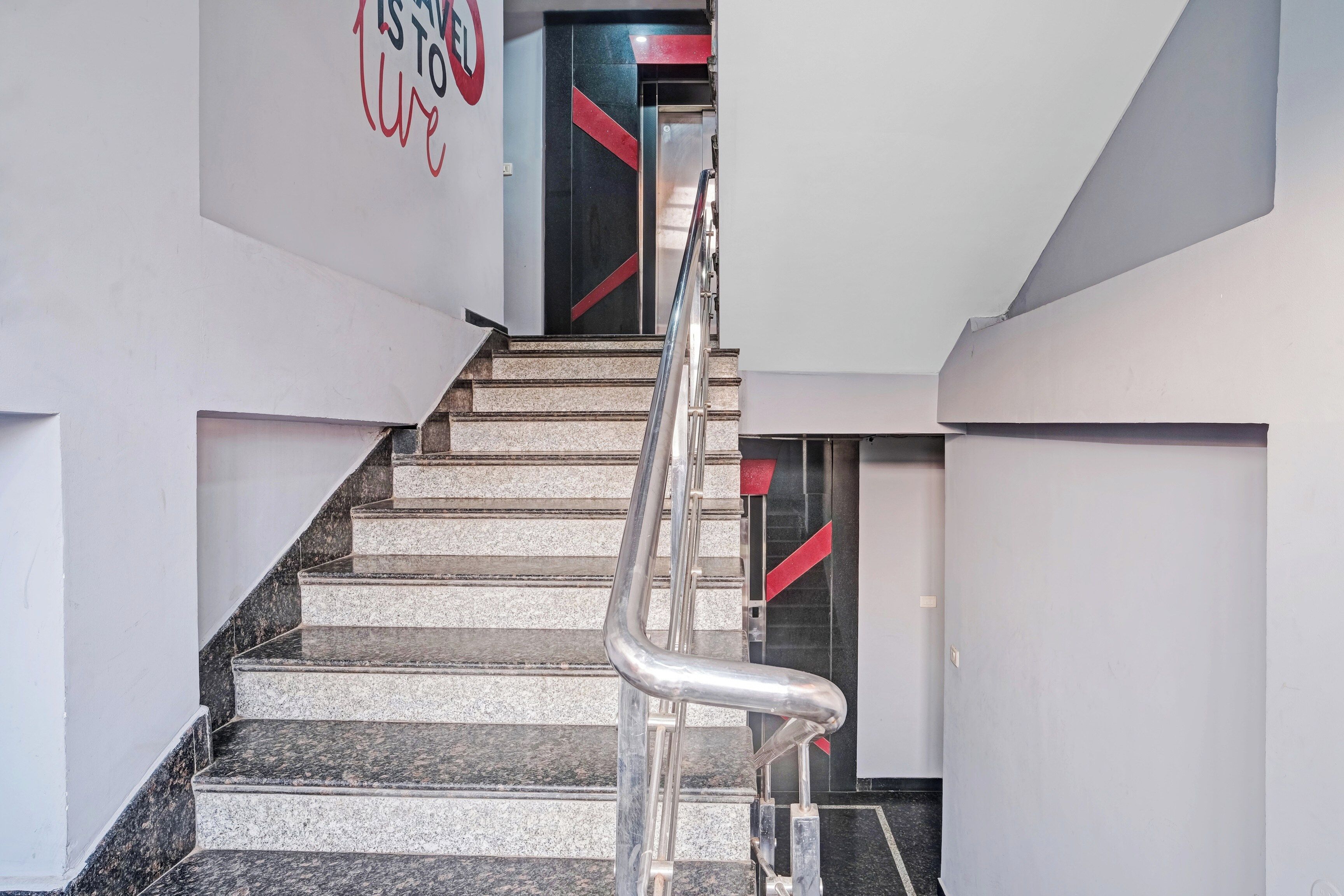 Una escalera con barandilla que lleva a una puerta con detalles rojos.