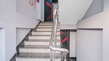 Una escalera con barandilla que lleva a una puerta con detalles rojos.
