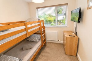 Ein Stockbett mit Kissen, ein Heizkörper, ein Fernseher und ein Holzschrank in einem Zimmer mit einem Fenster.