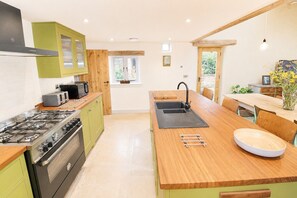 A modern kitchen with a gas stove, a sink, and wooden countertops. - Stonethwaite, Dalston - a luxurious, dog friendly, romantic barn conversion (Dalston)