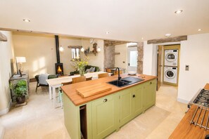 A modern kitchen with a central island, a dining area, and a built-in washing machine. - Stonethwaite, Dalston - a luxurious, dog friendly, romantic barn conversion (Dalston)