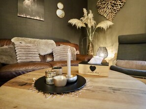 A cozy living room with a leather couch, a wooden coffee table with candles, and a tissue box. - Pretty gite with terrace near the Semois river (Alle-sur-Semois)