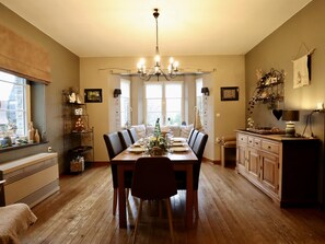Ein Esszimmer mit Holztisch, gedeckt für vier Personen, einer Chandelüster und einem Fenster mit Blick.
