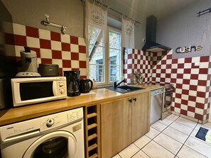 Cocina compacta con lavadora, microondas, cafetera y lavaplatos.