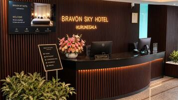 Un mostrador de recepción de hotel con una pantalla digital, un área de recepción y un cartel que enumera los servicios.