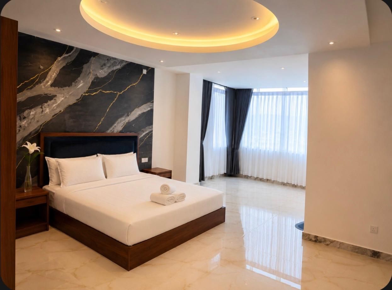 A modern bedroom with a large bed, a marble wall, and a ceiling light fixture.