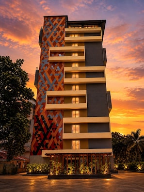 A multi-story hotel with a distinctive geometric facade, balconies, and a landscaped entrance area.