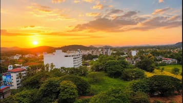 Paesaggio urbano con edifici, alberi e un tramonto.