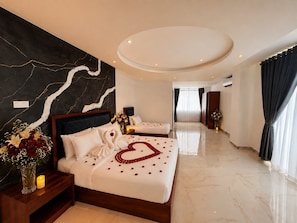 A hotel room with two beds, a marble floor, a large mirror, and a modern ceiling design.