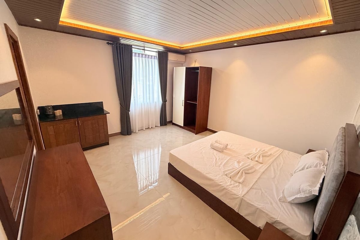 A modern bedroom with a bed, a wardrobe, a vanity, and a mirror.