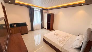 A modern bedroom with a bed, a wardrobe, a vanity, and a mirror.