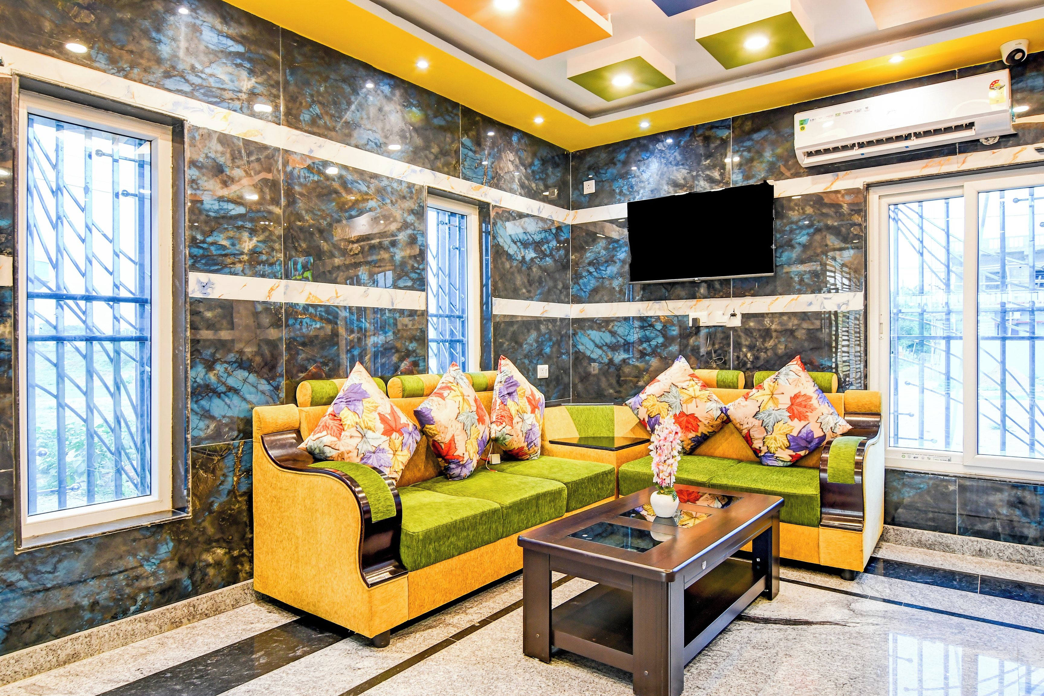 A modern lobby with a sofa set, a coffee table, and a flat-screen TV mounted on the wall.