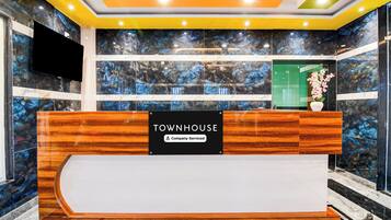 Una mesa de recepción con un letrero que dice 'TOWNHOUSE', paredes de mármol y un televisor de pantalla plana.