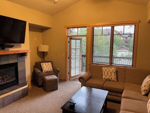 Una sala de estar con chimenea, televisión, sofá y mesa de centro.