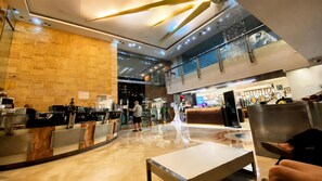 Eine moderne Lobby mit einer Rezeption, einer Sitzecke und einer Treppe zu einer oberen Ebene.