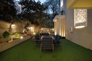 An outdoor patio with a dining table and chairs, surrounded by artificial grass and plants. - Relax at bait assel by spacey #102 (cairo)