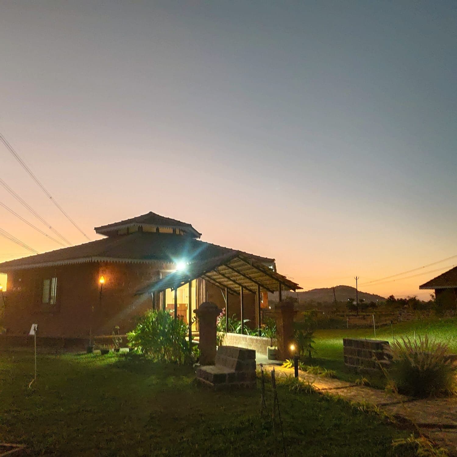 A house with a covered porch, a well-lit entrance, and a grassy yard.