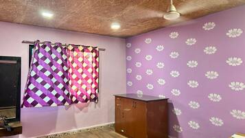 A room with a wooden ceiling, purple walls with white floral patterns, a wooden cabinet, and a curtain with a geometric pattern.