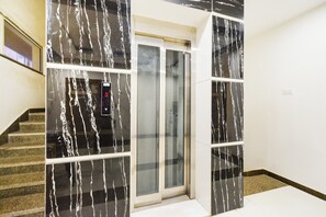 A staircase leading to a room with a glass door and a white wall.