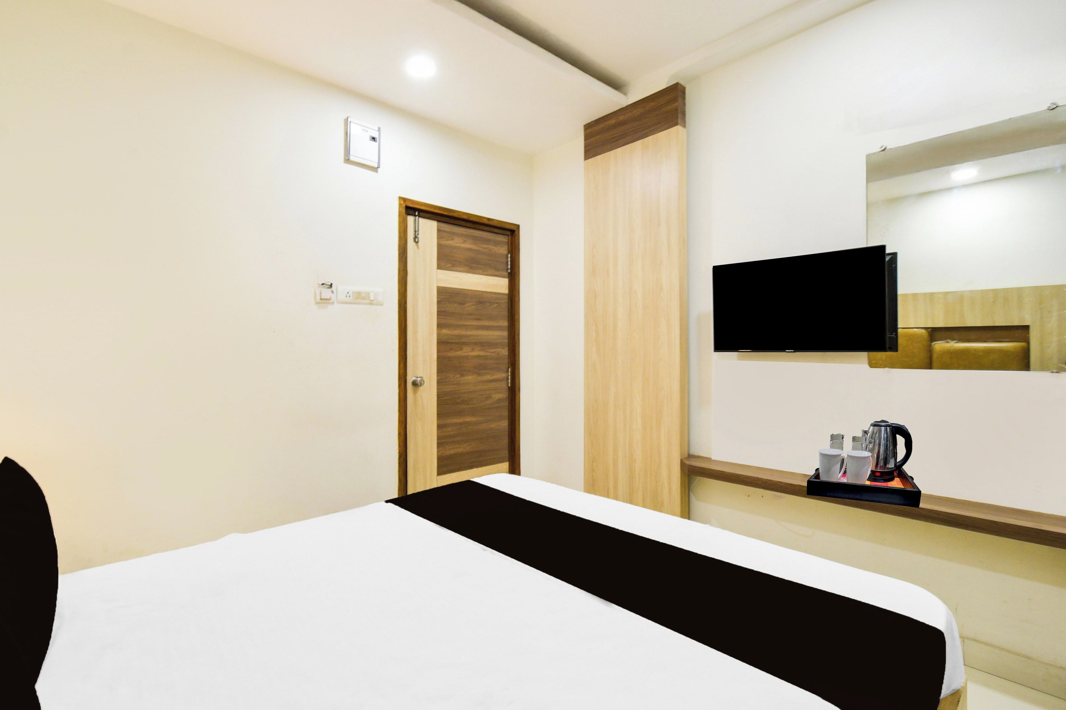 Een hotelkamer met een bed, een aan de muur bevestigde televisie en een koffieapparaat op een aanrecht.