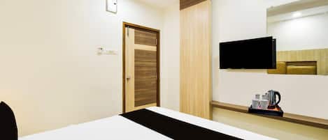 A hotel room with a bed, a television mounted on the wall, and a coffee machine on a counter.