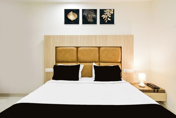 A hotel room with a bed, a nightstand, a lamp, and three wall art pieces.